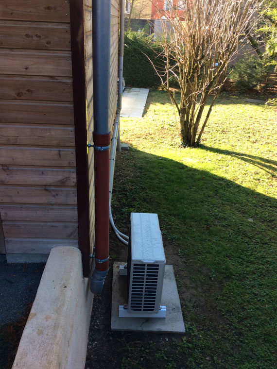 groupe de climatisation extérieur posé dans le jardin d'une maison